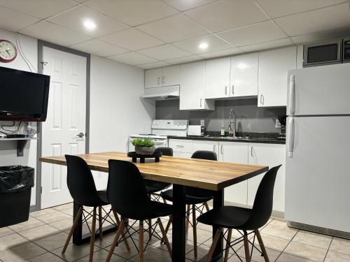a kitchen with a wooden table and chairs and a refrigerator at Les studios de la mer in Matane
