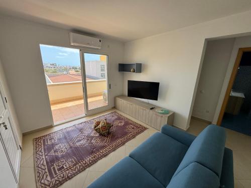 Una sala de estar con un sofá azul y una ventana grande. en CA AMARELA WI-FI FREE Sal Rei Boa Vista, en Sal Rei