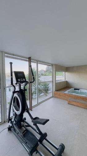 a gym with a treadmill in a room with windows at LOS PADEL Casa e Estúdio-Vitorino de Piães in Vitorino dos Piães