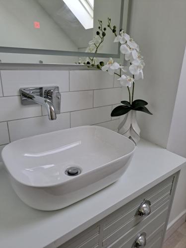 a white sink with a vase of flowers on a counter at Nanny lane loft in Church Fenton