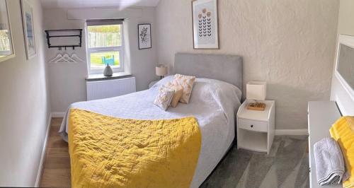a bedroom with a bed with a yellow blanket on it at Romantic log-burner Cornish Cottage private garden dogs welcome in Truro