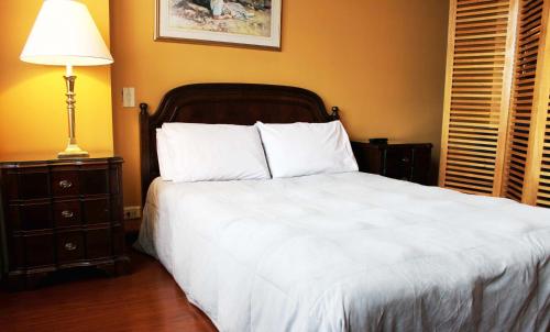 a bedroom with a large white bed with a lamp at Suites Studio 40 in Bogotá