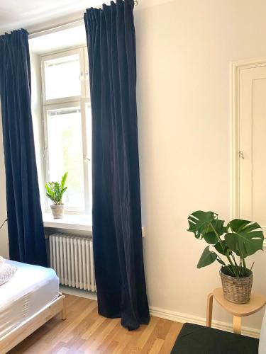 a bedroom with blue curtains and a window at Simply chic Kamppi !NEW! in Helsinki