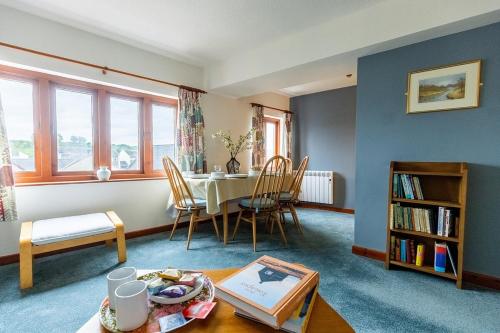 a living room with a table and chairs and a book shelf at KATHERINES COURT - Spacious Apartment with Rolling Hill Views in Kendal