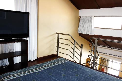 Habitación con cama, TV y balcón. en Suites Studio 40, en Bogotá
