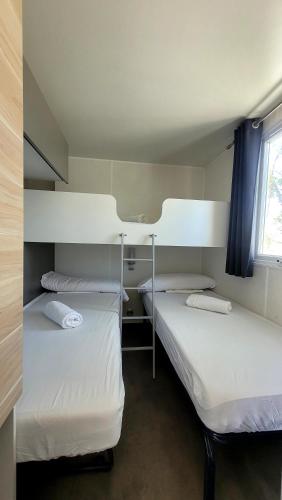 two beds in a small room with a window at Camping Costa Blanca in El Campello