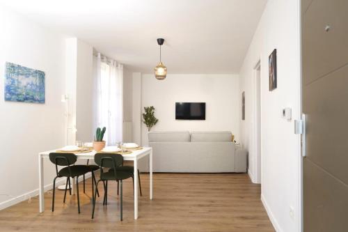 une salle à manger blanche avec une table et des chaises blanches dans l'établissement L'Escapade Montreuilloise, à Montreuil