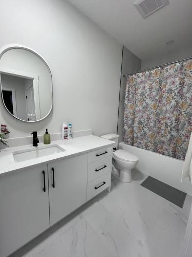 a bathroom with a sink and a toilet and a mirror at Haven Lodge, 2BR Brand New Basement Suite in Calgary