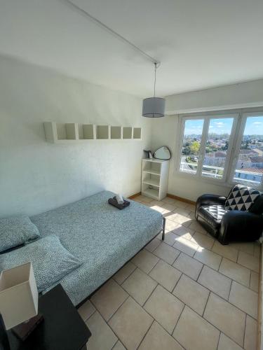 une chambre avec un lit, une chaise et des fenêtres dans l'établissement Spacieux T4 tout confort, vue sur Bordeaux, à Mérignac