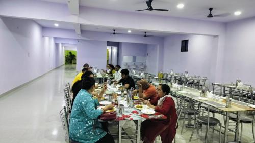 a group of people sitting at tables in a restaurant at Hotel Golden Buddha Inn Bodhgaya in Bodh Gaya