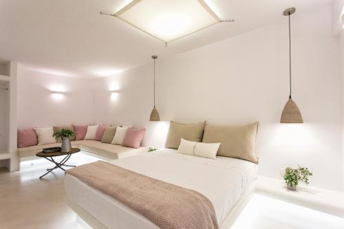 a white bedroom with a large bed and a couch at Anna Platanou Suites in Agia Irini Paros