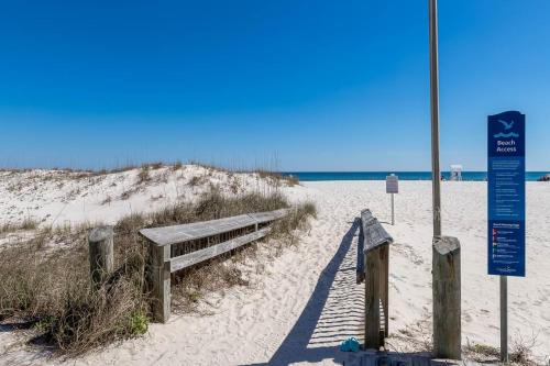 a bench on a sandy beach next to the ocean at Phoenix All Suites Hotel in Gulf Shores