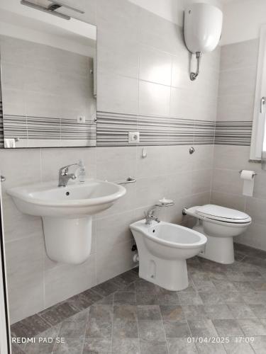 a white bathroom with a sink and a toilet at Family home in Donigala Fenughedu