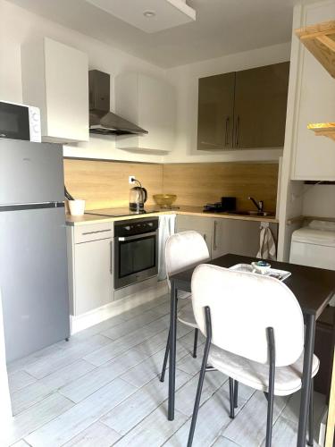 une cuisine avec une table, des chaises et un réfrigérateur dans l'établissement Joli Studio près de la mer, à Toulon