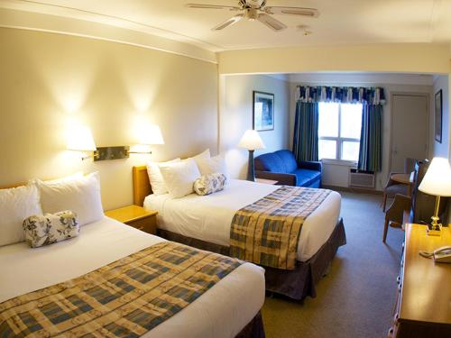 a hotel room with two beds and a blue chair at Silver Dart Lodge in Baddeck