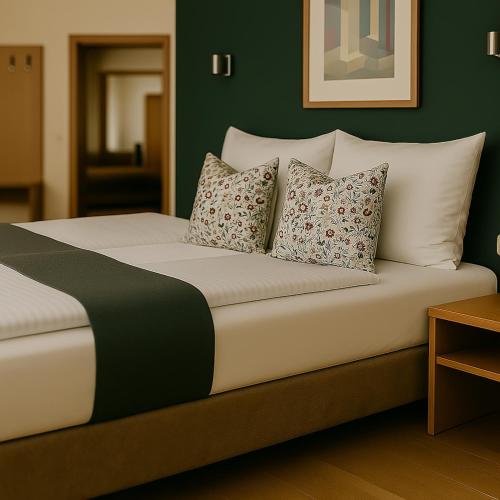 a bed with white pillows and a green wall at Hotel Schultheiss Hameln in Hameln