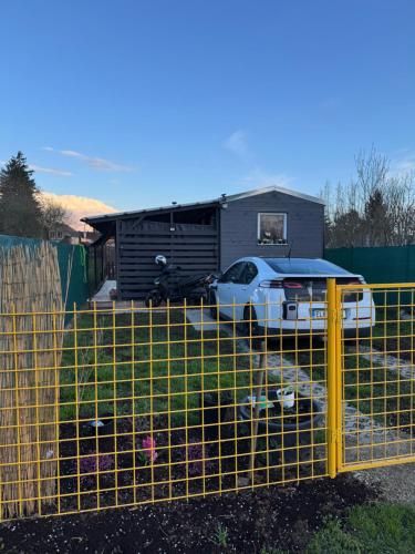 a fence with a car parked in front of a house at Tiny House v Balijském stylu v srdci Slovácka in Uherský Ostroh