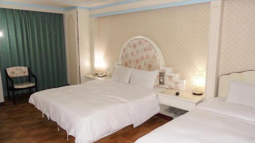 a hotel room with two beds and a chair at Modern Plaza Hotel in Kaohsiung