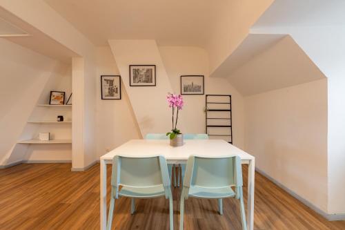 a dining room with a white table and blue chairs at Duplex la parenthèse enchantée in Saint-Omer