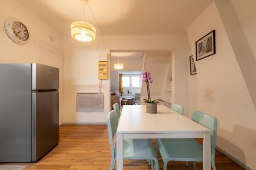 a kitchen and dining room with a table and a refrigerator at Duplex la parenthèse enchantée in Saint-Omer