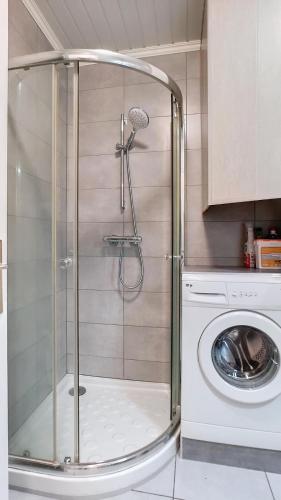 une douche avec une porte en verre à côté d'un lave-linge dans l'établissement Appartement élégant proche de la plage, à Mandelieu-la-Napoule