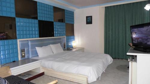 a hotel room with a bed and a television at Modern Plaza Hotel in Kaohsiung