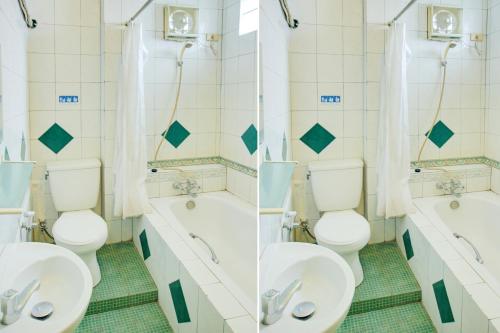 a bathroom with two toilets and a tub and two sinks at Townhouse Oak Palembang Near Jembatan Ampera Formerly Azzura Hotel in Palembang