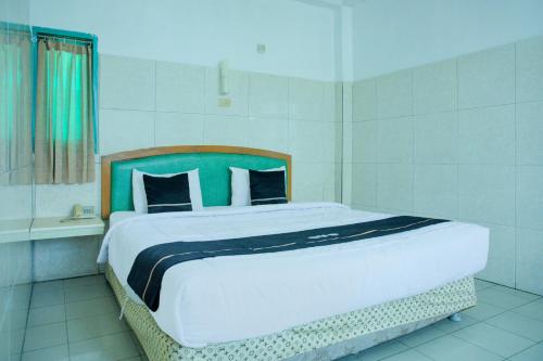 a bedroom with a large bed with a green headboard at Townhouse Oak Palembang Near Jembatan Ampera Formerly Azzura Hotel in Palembang