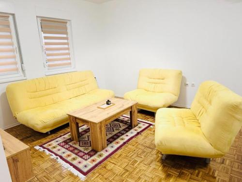 a living room with two yellow couches and a coffee table at Old Town Heritage in Gradačac