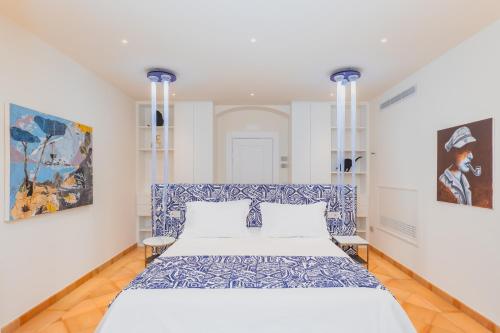 a bedroom with a blue and white bed and paintings at Five Positano in Positano