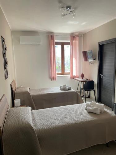 a bedroom with two beds and a table and a window at L'Uliveto B&B in Castelnuovo Cilento