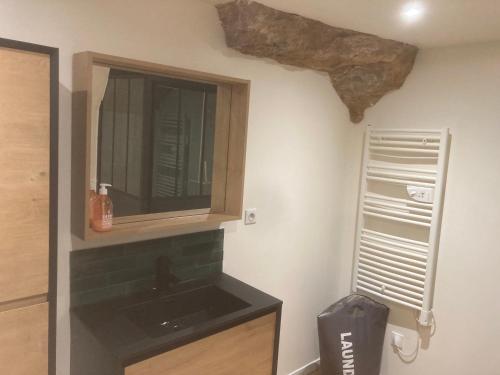 La salle de bains est pourvue d'un lavabo et d'un mur en pierre. dans l'établissement La Maison des Roches 4-6 personnes avec terrasse, à Sarlat-la-Canéda