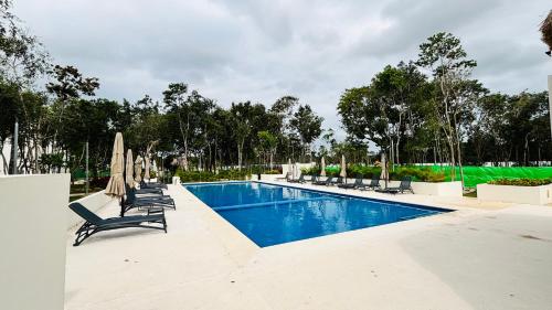 a swimming pool with lounge chairs and umbrellas at Amplio departamento 3 recámaras con pool ideal familias y grupos AC WiFi in Playa del Carmen