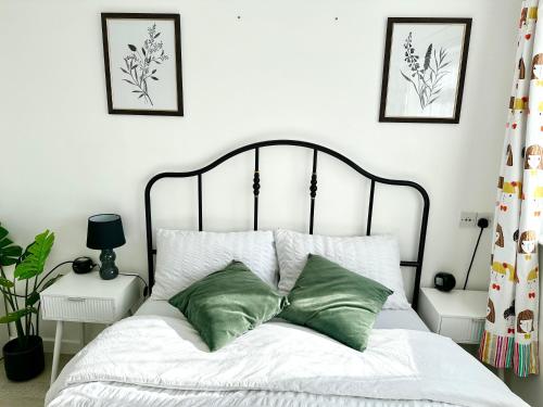 a bedroom with a bed with two green pillows at 5 bedroom detached house sleeps 13 spacious Parking 5 mins driving to Bicester Village in Bicester