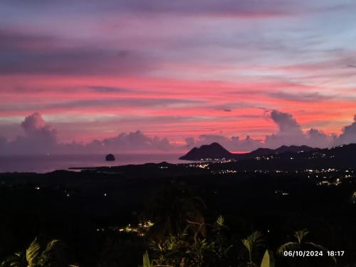 a sunset view of the ocean and a city at Nid d'Aigle Tropical in Rivière-Salée
