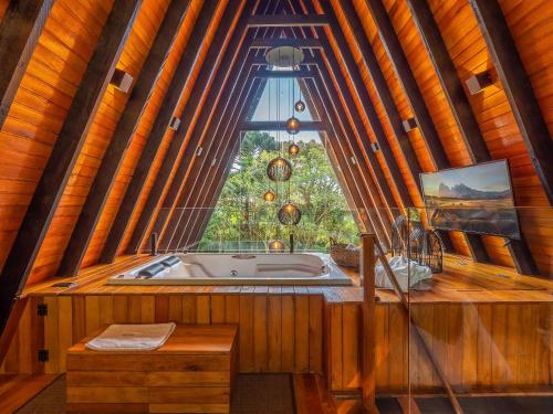 eine Badewanne in einem Raum mit einem großen Fenster in der Unterkunft Cabana Memórias in Gramado