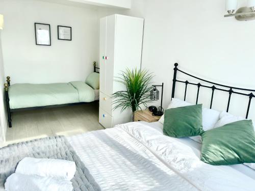 a white bed with green pillows in a bedroom at 5 bedroom detached house sleeps 13 spacious Parking 5 mins driving to Bicester Village in Bicester