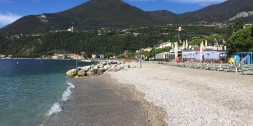 a beach with a group of chairs and the water at Gardalba in Toscolano Maderno
