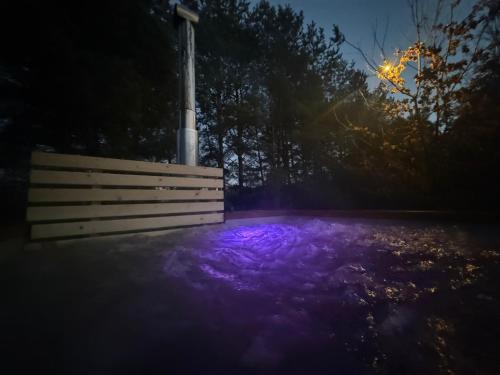 a fence and purple light at night at Dom w lesie przy stawach in Dylewo