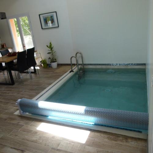 - un salon avec une piscine, une table et des chaises dans l'établissement Chambre d'hôtes du Pilou, à Queyssac-les-Vignes