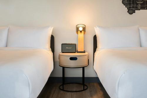 two beds with white sheets and a lamp on a table between them at Aloft Sacramento Airport Natomas in Sacramento