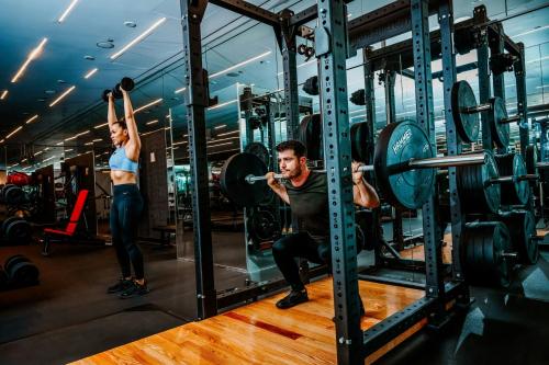 a man and a woman doing squats in a gym at SLS Hotel, a Luxury Collection Hotel, Beverly Hills in Los Angeles