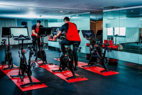 two men are riding on bikes in a gym at SLS Hotel, a Luxury Collection Hotel, Beverly Hills in Los Angeles