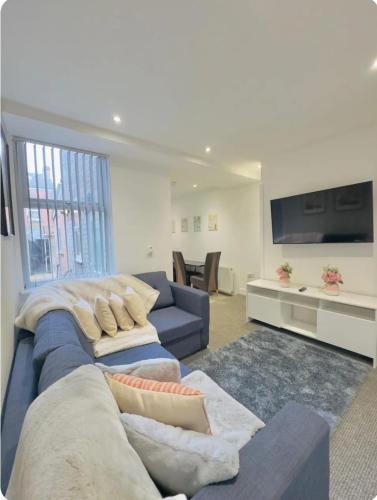 a living room with a blue couch and a tv at Room 5 Shared House in L6 in Liverpool