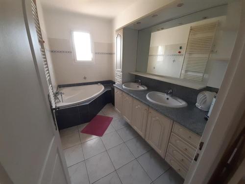 La salle de bains est pourvue de 2 lavabos, d'une baignoire et d'un miroir. dans l'établissement 4 bedroom villa pool entire place, à Salon-de-Provence