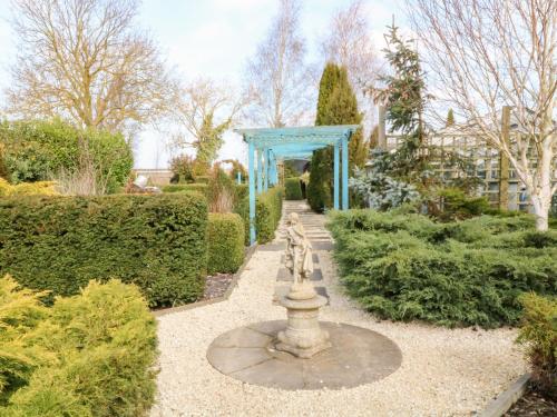 a garden with a fountain and a blue structure at Silver Birch Lodge in Bawtry