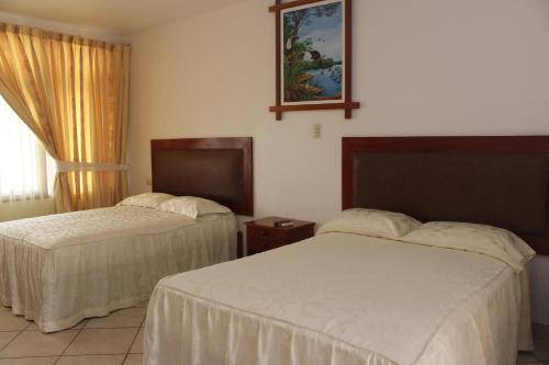 a hotel room with two beds and a window at Hotel Sol del Oriente Pucallpa in Pucallpa