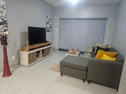 a living room with a couch and a flat screen tv at Zeeluli Mbabane CBD Apartments in Mbabane