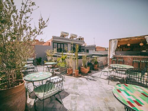 an outdoor patio with tables and chairs and plants at Riad Le Petit Joyau in Marrakech