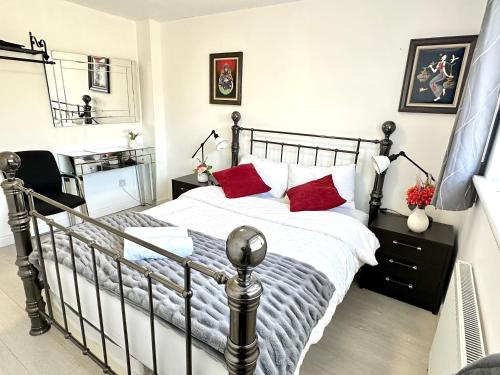 a bedroom with a black and white bed with red pillows at 5 bedroom detached house sleeps 13 spacious Parking 5 mins driving to Bicester Village in Bicester